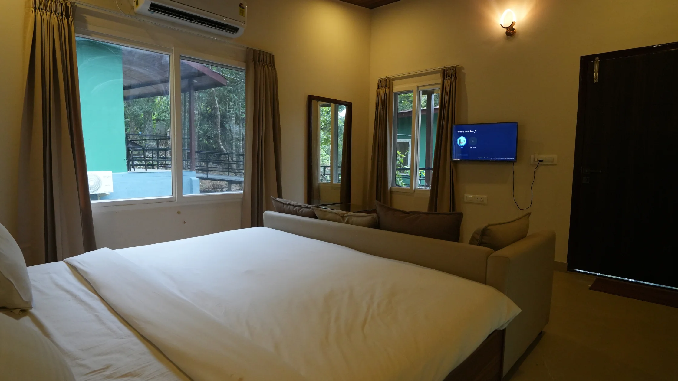 comfortable-resort-room-at-a-sakleshpur-resort-with-a-cozy-bed-sofa-tv-and-views-of-lush-greenery